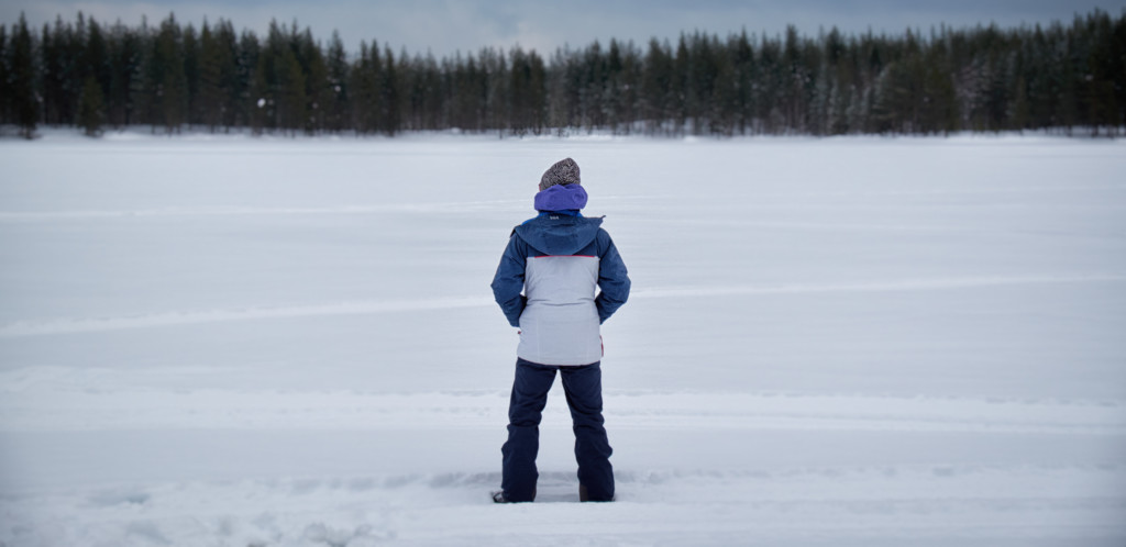 En ensam person står på isen i snölandskap