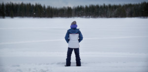 A person is standing alone on a lake in a winter landscape